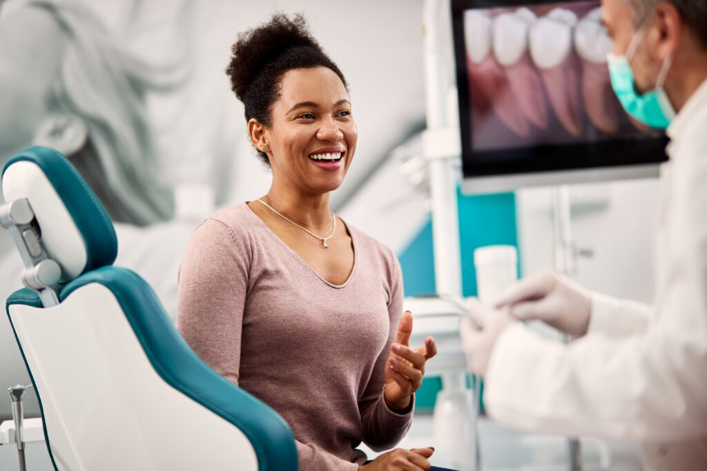 Happy black woman talks to her dentist during appointment at dental clinic.